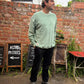Man standing outdoors with a brick wall wearing a Sea Green jumper.