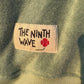 Label with 'The Ninth Wave' text on a green fabric background.