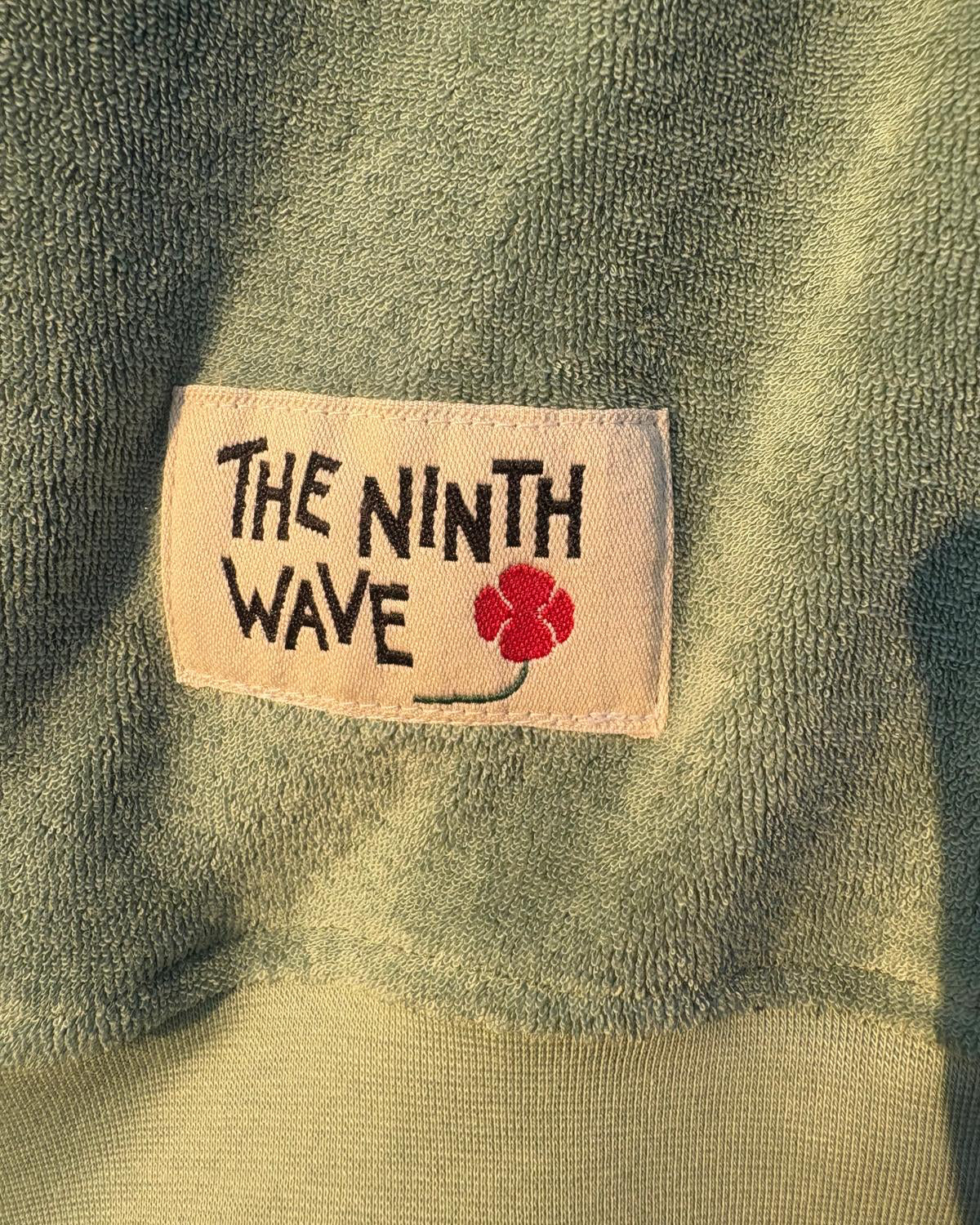 Label with 'The Ninth Wave' text on a green fabric background.